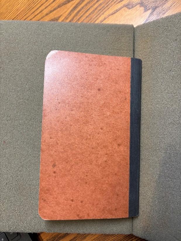 The front cover of a small, brown paperbound diary on top of a bookrest in the MHS reading room.